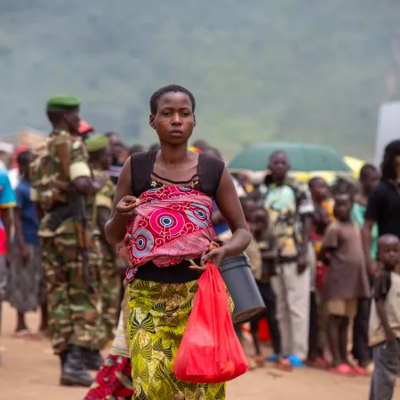 A woman carrying a baby walks through a crowded path    