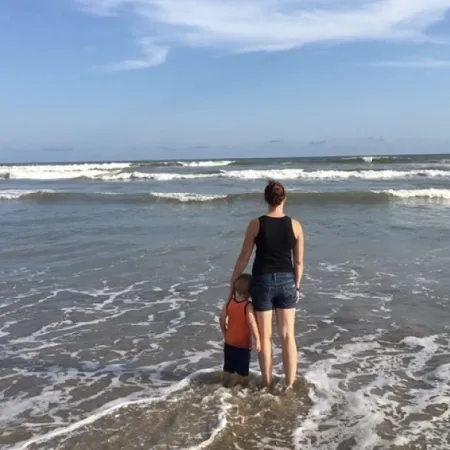 Bethany stands on a beach in Ghana with her son.
