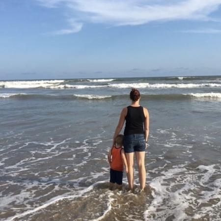 Bethany stands on a beach in Ghana with her son.