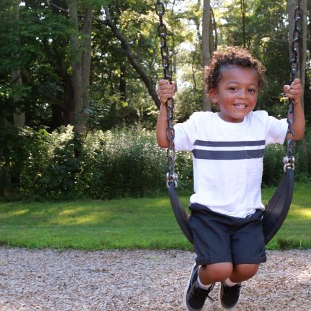 Young boy smiling on a swing set