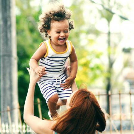 Child playfully thrown in the air by mother