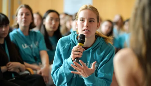 girl in a blue t-shirt speaking into the class