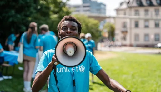 Youth in a blue UNICEF t-shirt speaking into a megaphone.