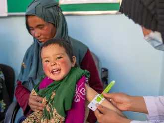 A girl smiles while getting the arm circumference measured for malnutrition. 