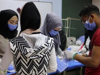 Syrian youths work to make cloth masks.