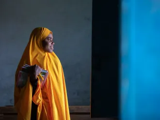 A girl wearing yellow uniform in Somalia looks hopefully into the light 
