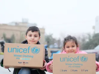 Two children show off their UNICEF supplies in Lebanon.