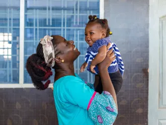 A woman holds up a smiling baby.