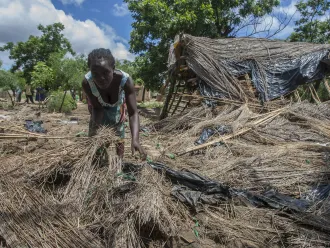 A woman searches through her destroyed home.