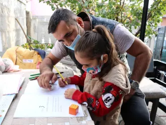 Hazir helps his daughter Naida study.