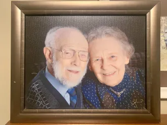 A photo of a framed photo of an elderly couple looking at the camera smiling with their heads touching. 