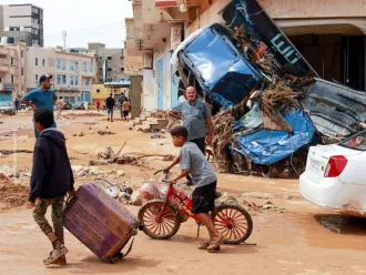 A boy pulls a suitcase past debris in a flash-flood damaged area in Derna, Libya.