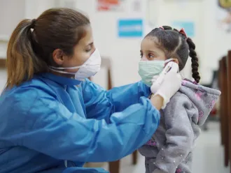 Nurse in Lebanon helping little girl put on face mask
