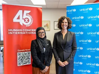 Mahmuda Khan, CEO of Human Concern International and Sevaun Palvetzian, President and CEO of UNICEF Canada pose for a photo in front of HCI and UNICEF Canada banners.