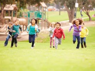 Seven children running towards the camera in a playground
