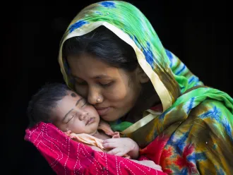 A Bangladeshi mother holds her newborn daughter up to her face.