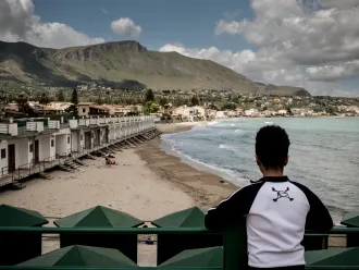 A boy who is an unaccompanied minor looks across the beach in Trabia, Italy, on May 14, 2016. 