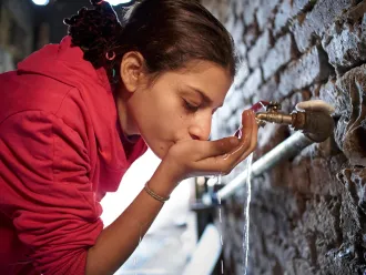 A girl drinks clean water from a tap.