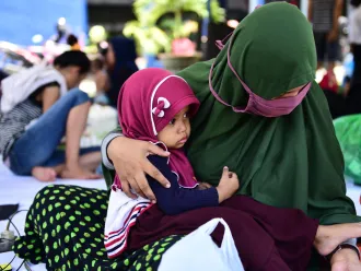 A baby sits in her mother's lap at a temporary shelter in Palu in 2018.