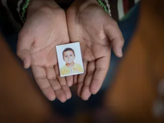 A Syrian boy holds a photo of himself in kindergarten.