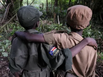 Two former child soldiers pose with their arms around each other.