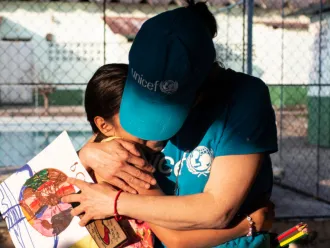 A UNICEF aid worker gives a hug to a Mexican girl.