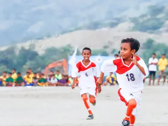 Two boys take part in a soccer match.