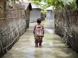  Child wades through water on her way to school in Bangladesh