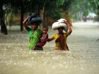 Two women and a small child wade through floodwaters in Bangladesh.