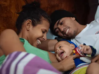 Two parents cuddle with their infant.