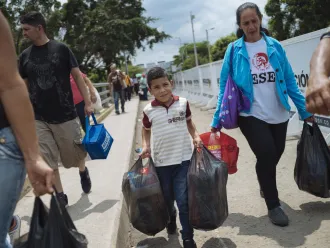 Luisyan Diaz, 7 years old, helps his grandmother and mother cross the border on the Simon Bolivar Bridge in Colombia, from their home in Venezuela.