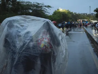 Children shelter under a plastic tarp while waiting to cross the border from Venezuela.