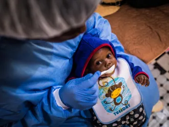 Christ-Vie, an Ebola orphan, is fed by a caretaker in Butembo.