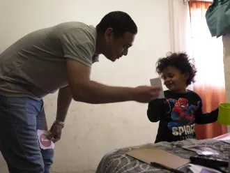 A father helps his son brush his teeth.