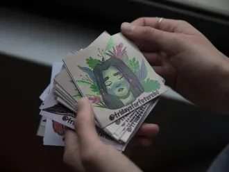 A girl holds stickers with the hashtag Fridays for Future printed on them.