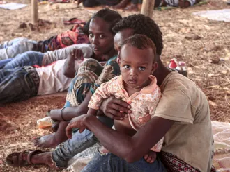 An Ethiopian refugee child who fled fighting in Tigray province sits holding a child in a hut at the Um Raquba camp in Sudan's eastern Gedaref province, on 16 November 2020. Sudan – one of the world's poorest countries, now faced with the massive influx – has reopened the camp, 80 kilometres (50 miles) from the border. It once housed refugees who fled Ethiopia's 1983-85 famine that killed over a million people.