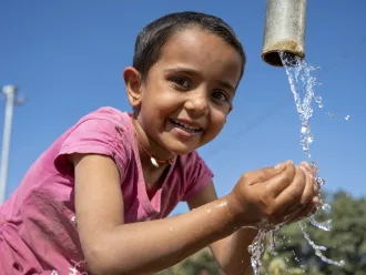 Jhanu (5 yrs) drinks water from the village hand pump near her anganwadi. 