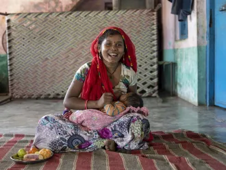 A young mother breastfeeds her newborn baby at a tea estate in India.