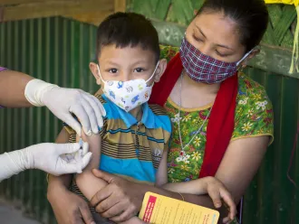 A child sits on his mother's lap as he receives an MMR vaccine.