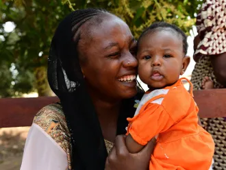 A mother smiles as she hugs her baby.