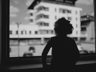 La petite fille de trois ans, Lana, regarde par la fenêtre son jardin d'enfants