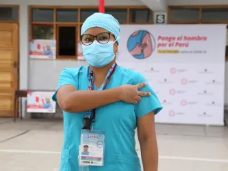 A health worker gives the V for Vaccinated sign after receiving their first COVID-19 vaccine in Peru.