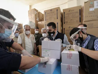 On 21 April 2021, staff members of UNICEF and WHO togerther with local partners, inspect the first shipment of COVID-19 vaccines for the COVAX Facility in Jdaydet Yabous, a village situated on the border between Syria and Lebanon, in the rural area of Damascus.