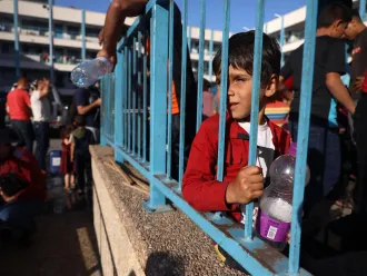 Palestinian boy holding empty water bottles and asking where he could find clean drinking water.