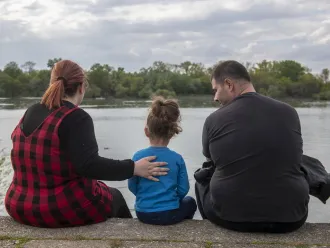 A family sits on a riverbank in Serbia.