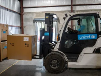UNICEF Haiti supply officer Jeremie Thomas fork-lifts a solar fridge in the warehouse in Port-au-Prince.