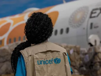 A UNICEF staff member watches as COVID-19 vaccines are unloaded from a plane.