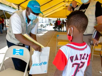 Marc receiving an education kit from UNICEF staff at the Port au Prince airport upon his arrival in Haiti.23 September 2021 – Port au Prince Airport, Haiti. Haitian families being expelled from the United States border to Haiti through several flights during the day.  UNICEF is on the ground at the airport and provides returning children with psychosocial support, protection services and education supplies, in coordination with national authorities and the International Organization for Migration.  