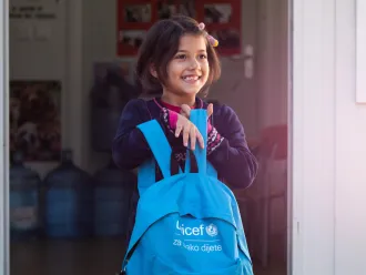 A young girl holds her UNICEF-supplied backpack.