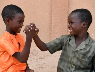 Two boys hold hands outside a school in Niger